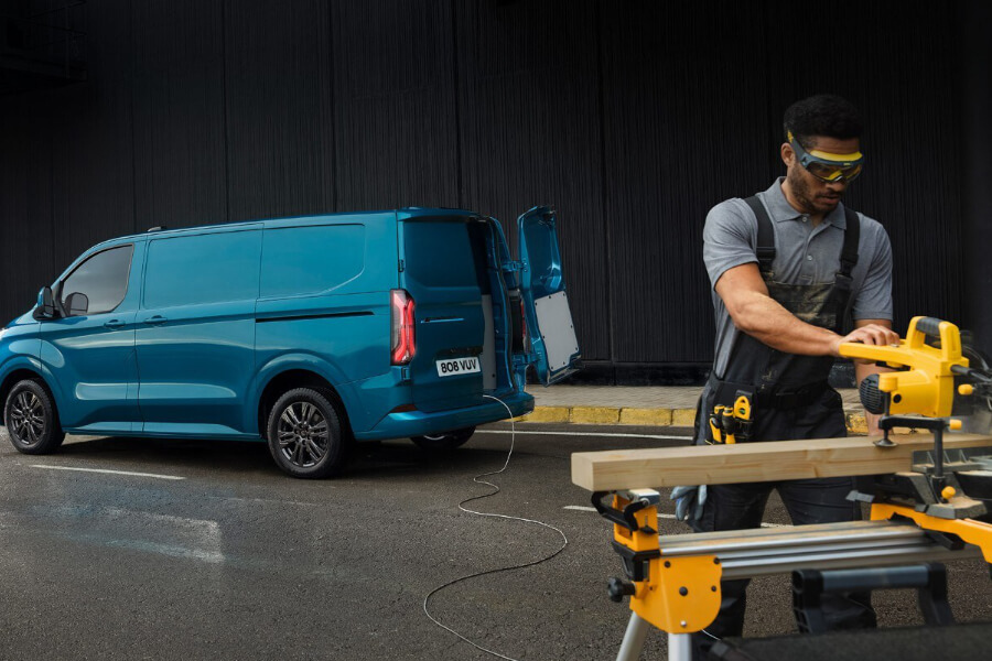 Ford E-Transit Custom Blau ¾-Seitenansicht mit geöffneter Hecklappe und Pro Power Stromversorgung für Handwerker im Vordergrund